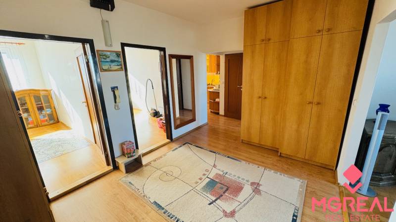 A hallway in a 4-room apartment with a wooden decor floor and a large wardrobe.