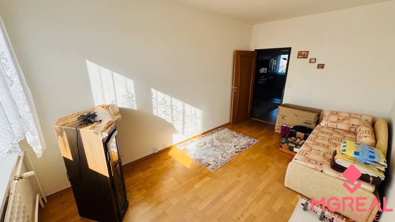 A room in a 4-room apartment, wooden decor flooring, carpet, sofa, furniture.
