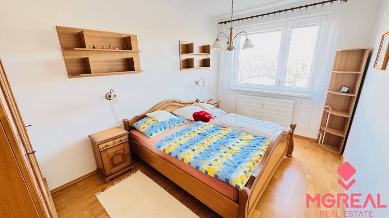 A bright bedroom in a 4-room apartment with a wood-patterned floor and a double bed.