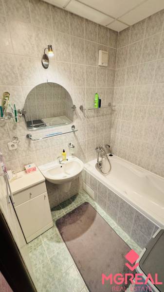 A bathroom in a 4-room apartment with a bathtub, sink, and tiles with a light decor.