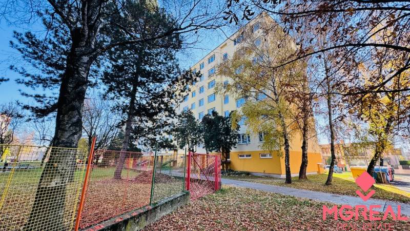 An apartment building on I. Krasko Street in Prievidza surrounded by trees in an autumn setting.