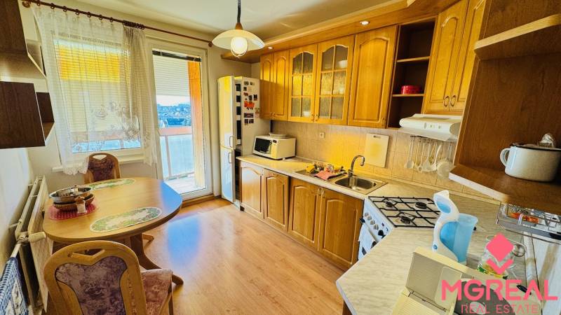 A kitchen in a 4-room apartment with a wooden decor floor and a wooden kitchen unit.