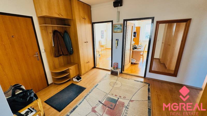 Entrance hall of a 4-room apartment with wood-patterned flooring, carpet, and wooden furniture.