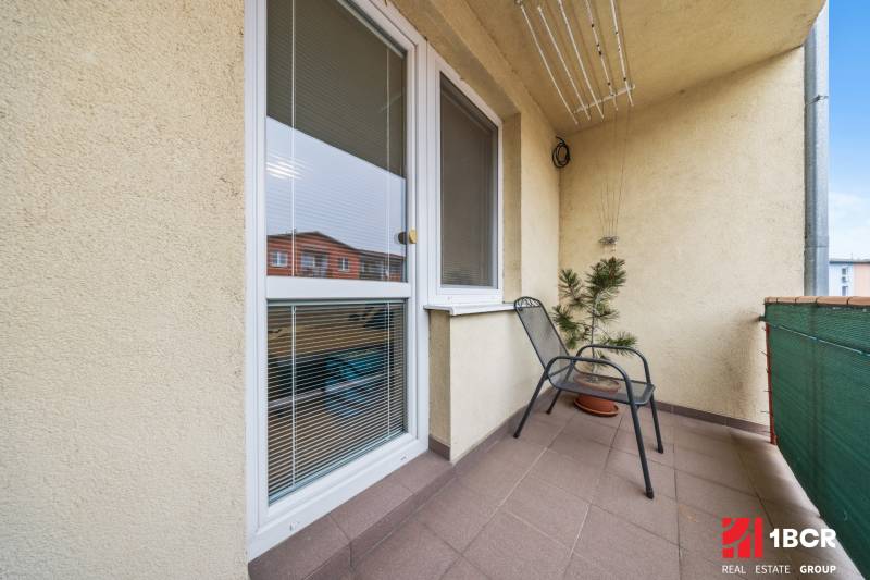 The balcony of a 2-room apartment on Veltlínska Street in Pezinok with a flower and a chair.