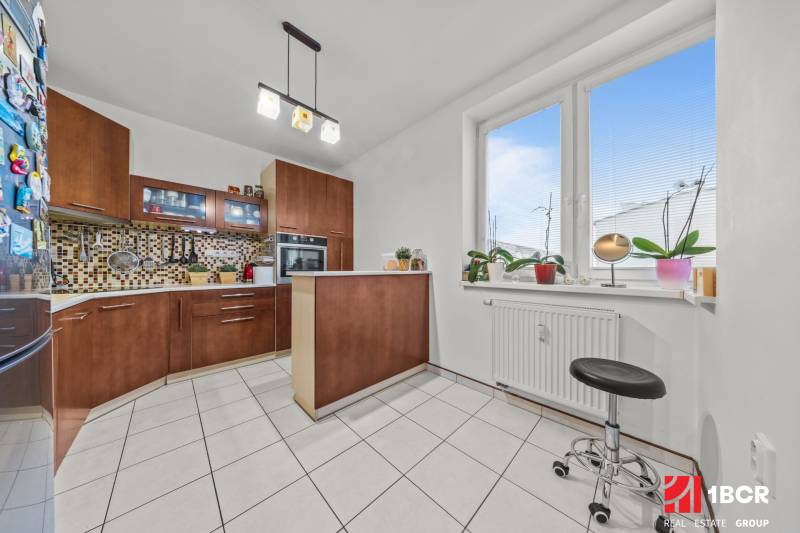 A kitchen in a 2-room apartment with tiles, a window, and a kitchen unit.