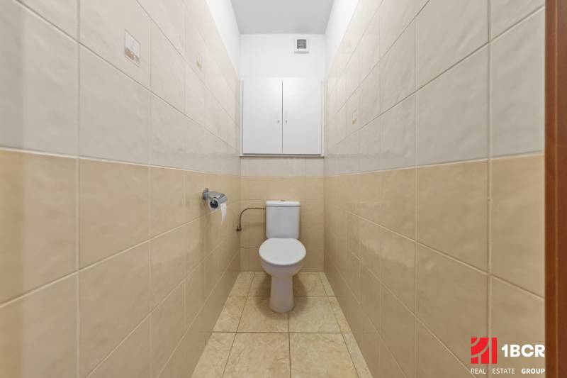A bathroom with tiles in a 2-room apartment, cream tiles on the wall.