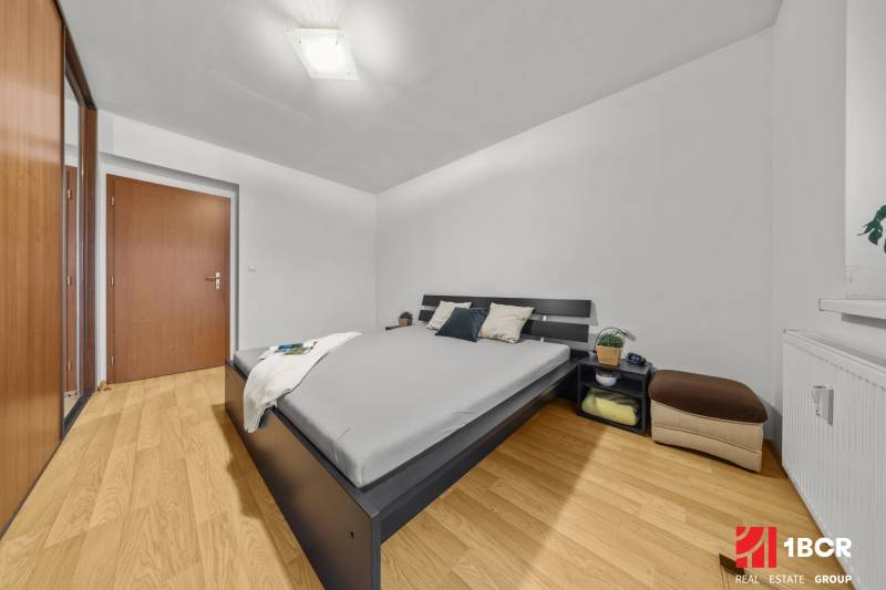 Bedroom in a 2-room apartment with a bed, wardrobe, and floor with a wooden decor.