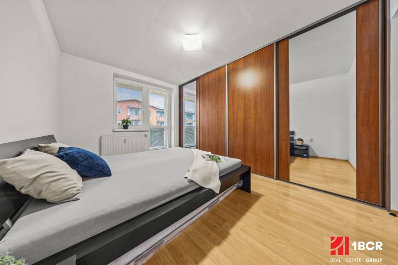 A bedroom with a bed, built-in wardrobe, and wooden decor flooring in a 2-room apartment.