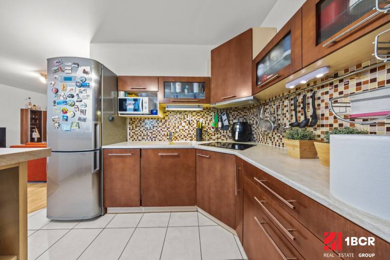 A kitchen with tiles, a decent kitchen unit, a refrigerator, and appliances in a 2-room apartment.