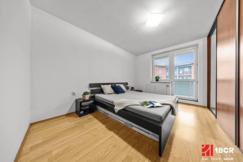 Bedroom in a 2-room apartment with a bed, nightstands, and a floor with a wood decor.