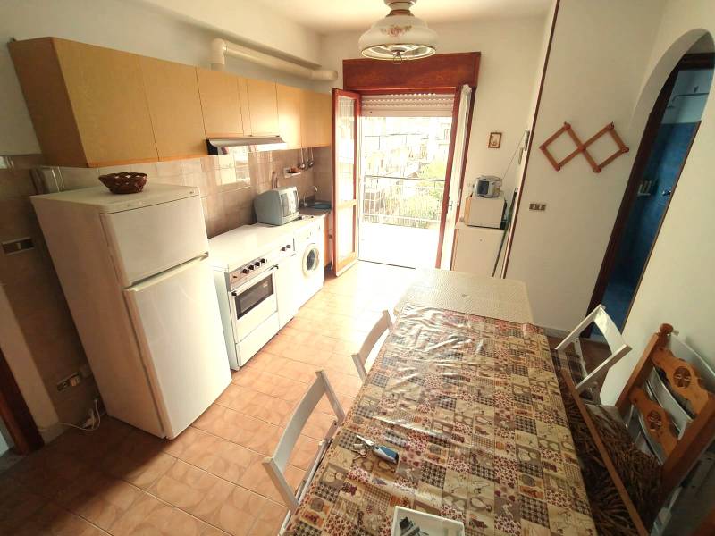 A 3-room apartment kitchen with tiles, a stove, a refrigerator, and a dining table.