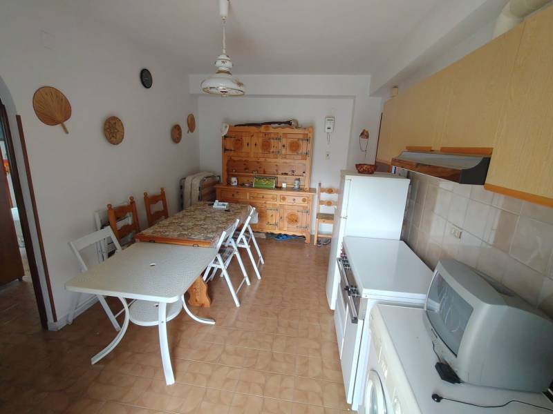 A kitchen with a dining table and chairs in a 3-room apartment with a wooden decor floor.