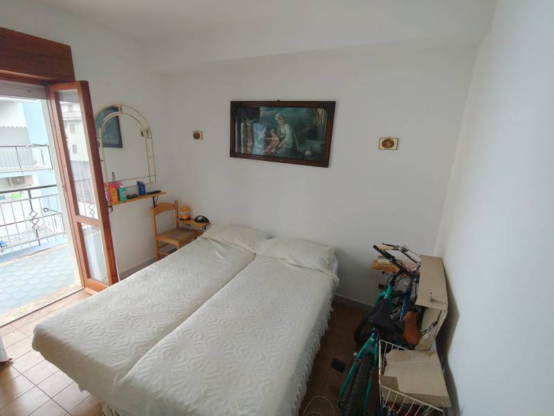 A bedroom in a three-room apartment with light walls and a balcony.