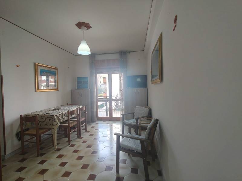 Dining room in a two-room apartment with a tiled floor and simple furnishings.
