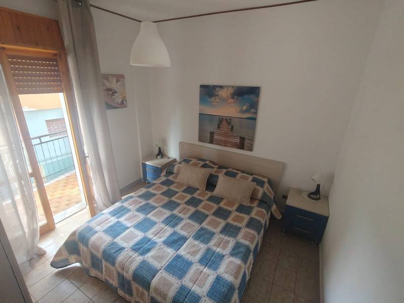 Bedroom in a 2-room apartment with a bed, nightstands, and art on the wall.