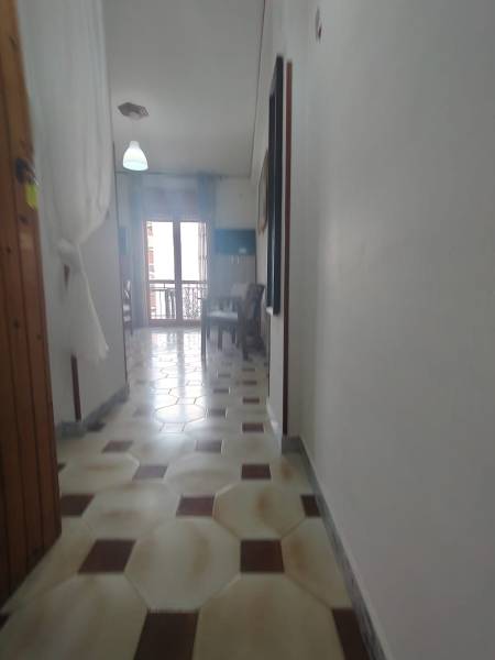 A narrow hallway in a 2-room apartment, light floor, table by the window.
