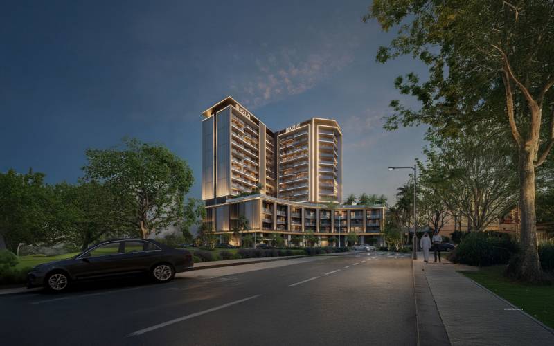 Night scene of a building in Downtown Jabel Ali, illuminated trees and a parked car.