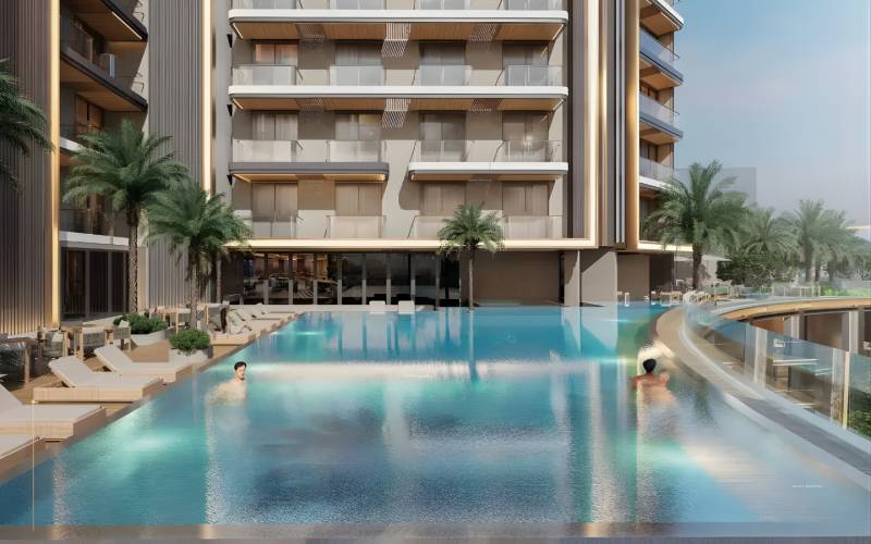 The exterior of the building in Downtown Jabel Ali with a pool, palm trees, and loungers.