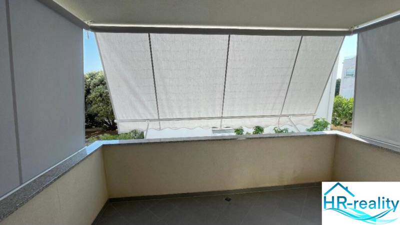 Balcony of a 3-room apartment in Novalja with retracted awnings and a view of the garden.