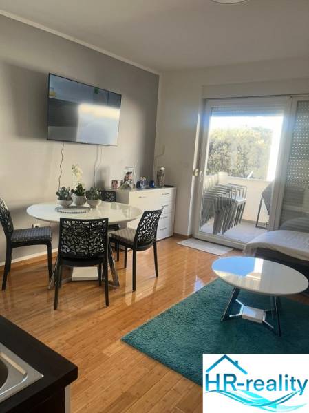 Living room of a three-room apartment with a wooden decor floor and a balcony.