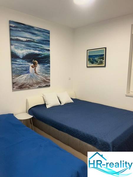 Bedroom in a 3-room apartment with blue beds, white pillows, and paintings on the wall.