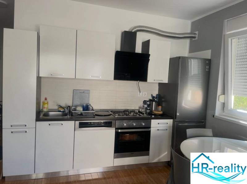 A kitchen with white cabinets, a stainless steel refrigerator, wood-patterned flooring, 3-room apartment.