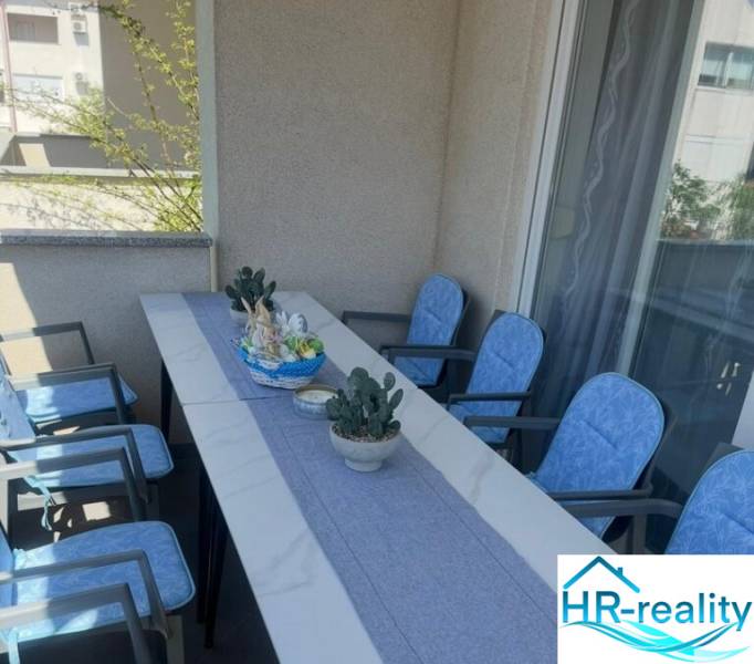 A balcony in a 3-room apartment with a table, seating, and decorations, ideal for relaxation.