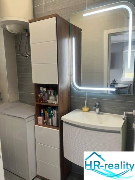 Bathroom in a 3-room apartment with a sink, mirror, and cabinet for toiletries.