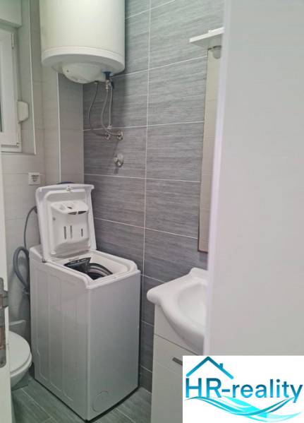 Bathroom with a washing machine and a sink in a 3-room apartment, light gray tiles.