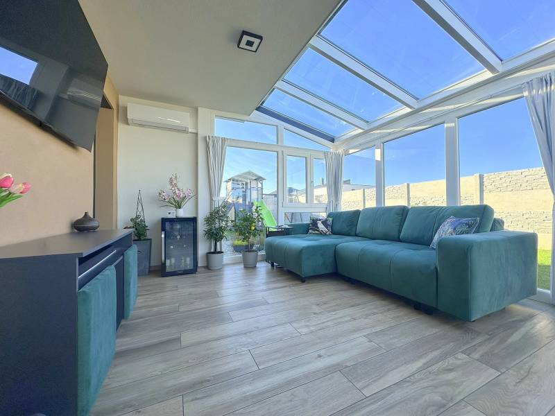 Bright winter garden in a family house with a wooden decor floor and a green sofa.