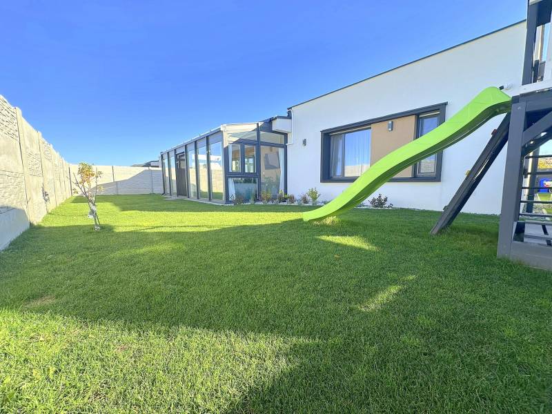 A family house in Mosonmagyaróvár with a glass veranda and a green slide in the garden.