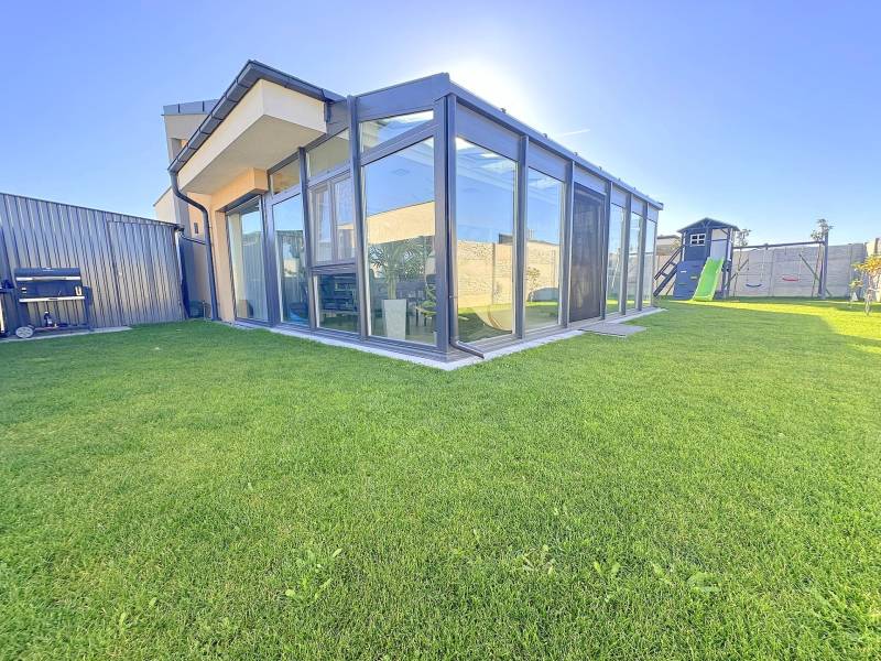 A glazed terrace and a children's playground at a family house in Mosonmagyaróvár.