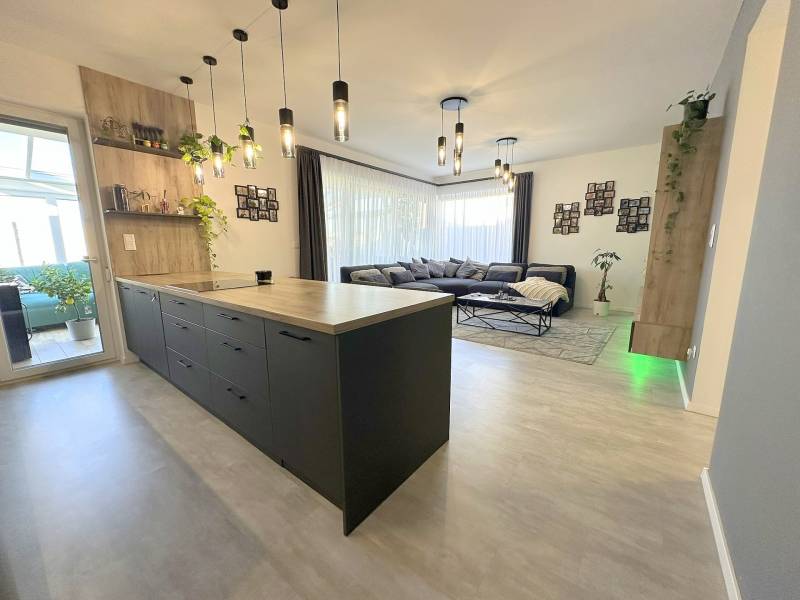 A kitchen with an island and a living room in a family house with a comfortable sofa.