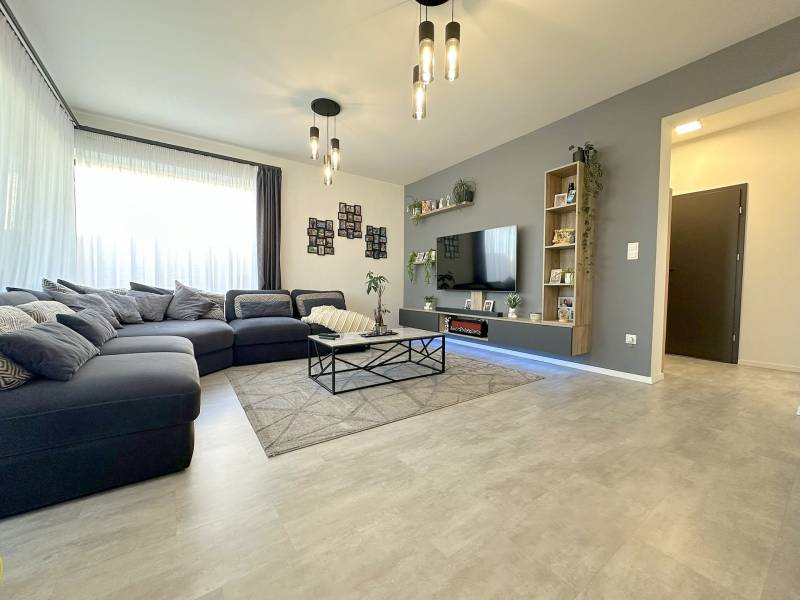 Living room in a family house with a large sofa and a floor with a wooden decor.