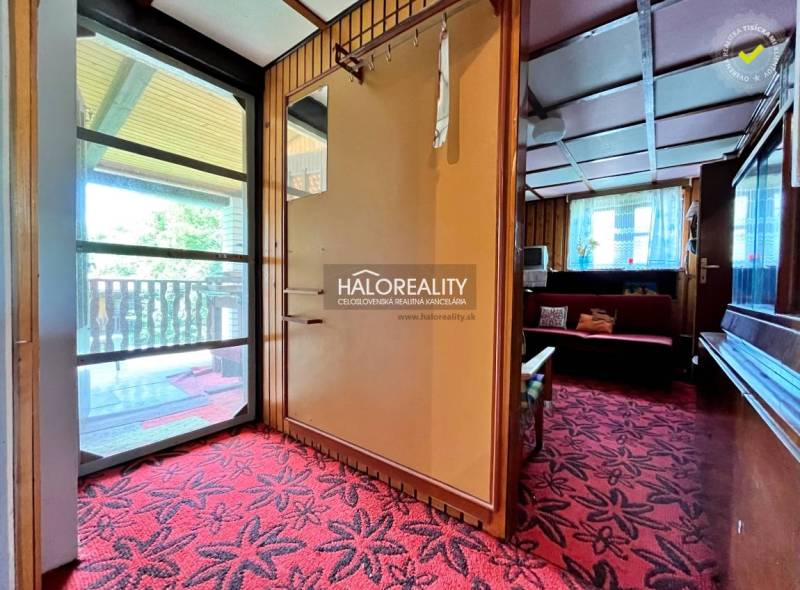 A cottage with a terrace and a red carpet, stone elements, and wooden wall decor.