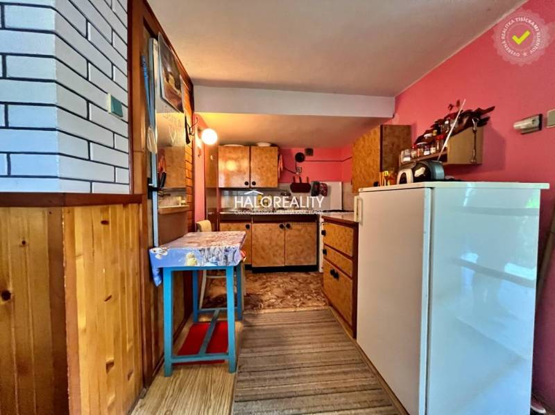 A kitchen in a cottage with a wooden decor floor and pink walls.