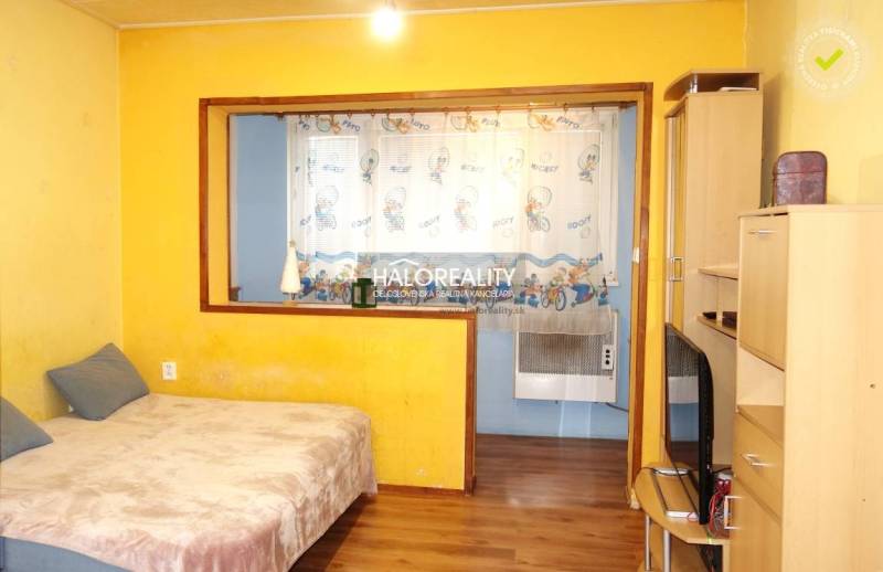 Yellow walls and curtains with a children's motif in a studio apartment, floor with wooden decor.