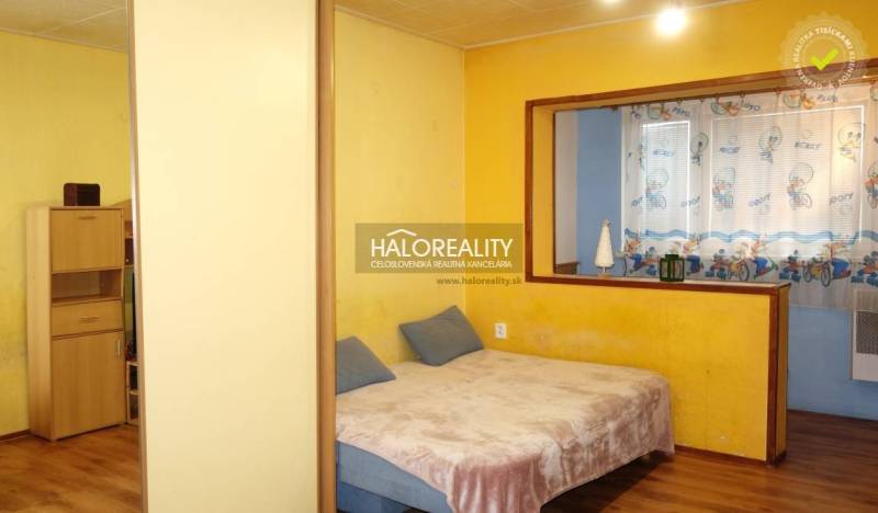 1-bedroom apartment with yellow walls, a bed, and floor decor, blue alcove.