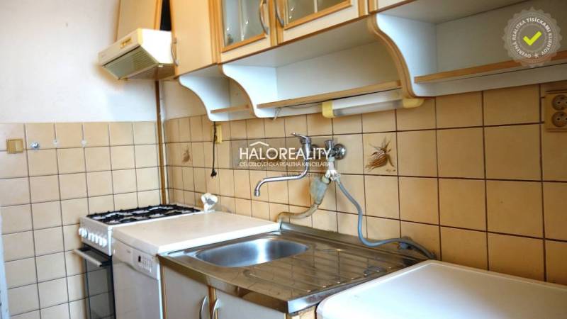 A kitchen in a studio apartment with a gas stove, tiled backsplash, and storage cabinets.