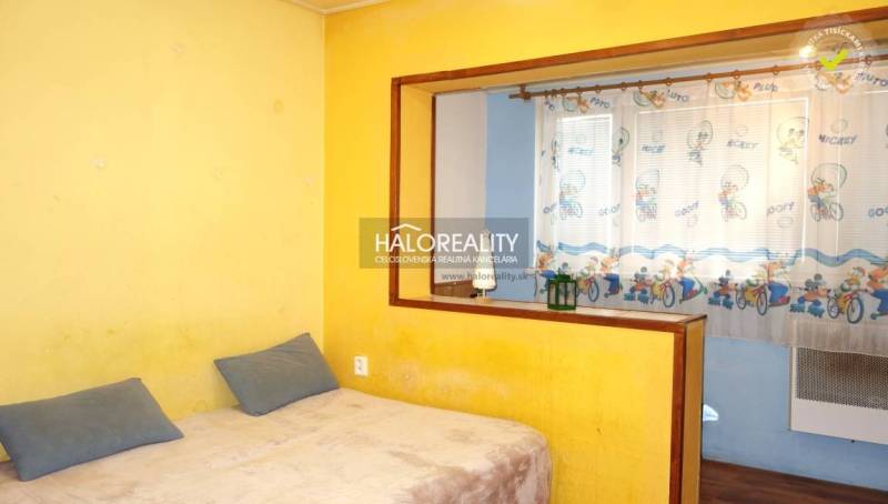 Yellow walls and a bed with pillows in a studio apartment.