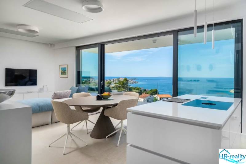 A holiday apartment with a sea view, bright interior with large windows and a kitchen island.