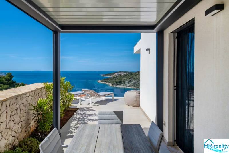 View from a holiday apartment in Rogoznica. Table, chairs, and loungers facing the sea.