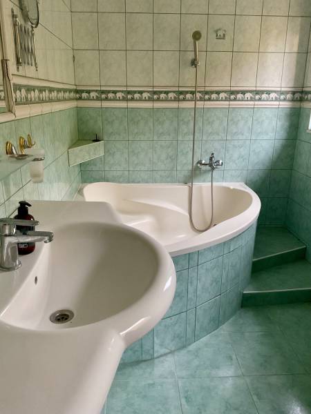 A bathroom with a corner bathtub and green tiles on recreational grounds.