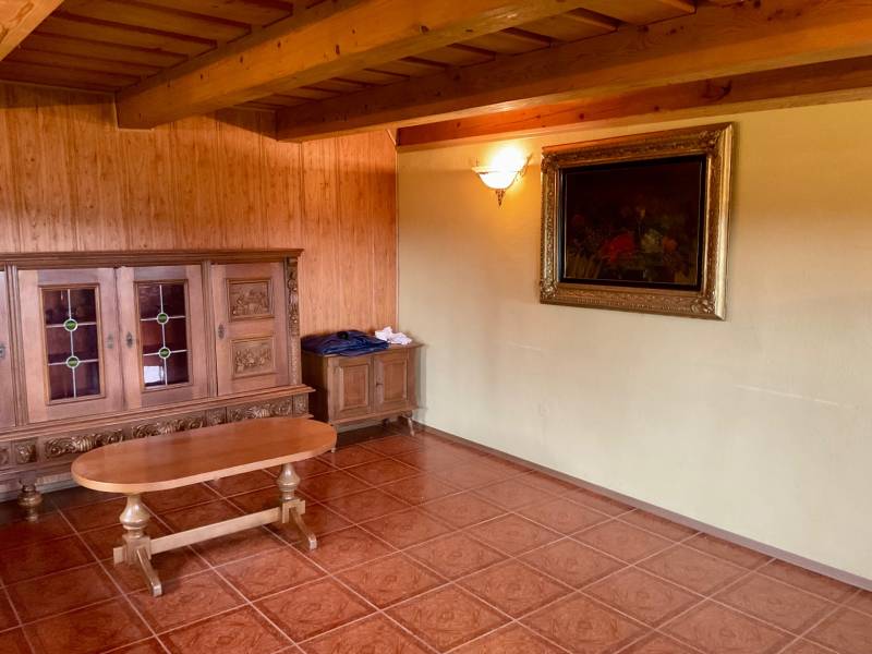 A room with historical furniture, a painting on the wall, and a wooden-decor floor on recreational grounds.