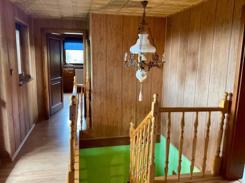 Wooden interior with railing, chandelier, and floor with wood decor at Recreational Grounds.