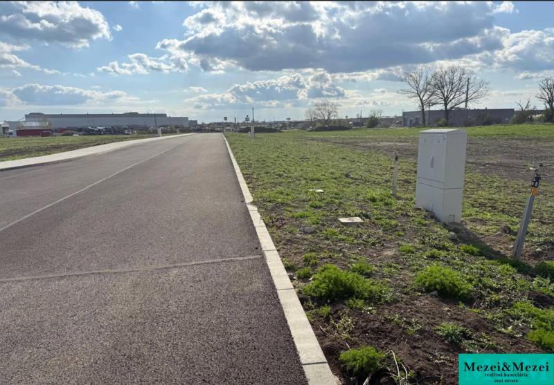 A view of commercial land in Trnava with an asphalt road and green areas.