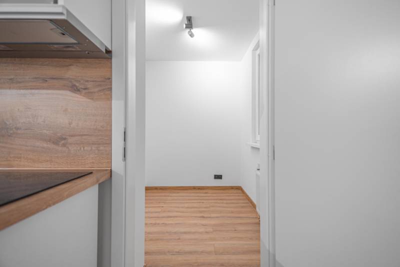 Interior of a 1-room apartment with white walls and a floor with a wood decor.
