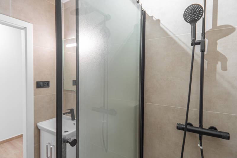 Bathroom in a studio apartment with a modern shower and sink.