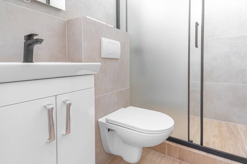 Bathroom with a sink, shower, and toilet in a studio apartment.