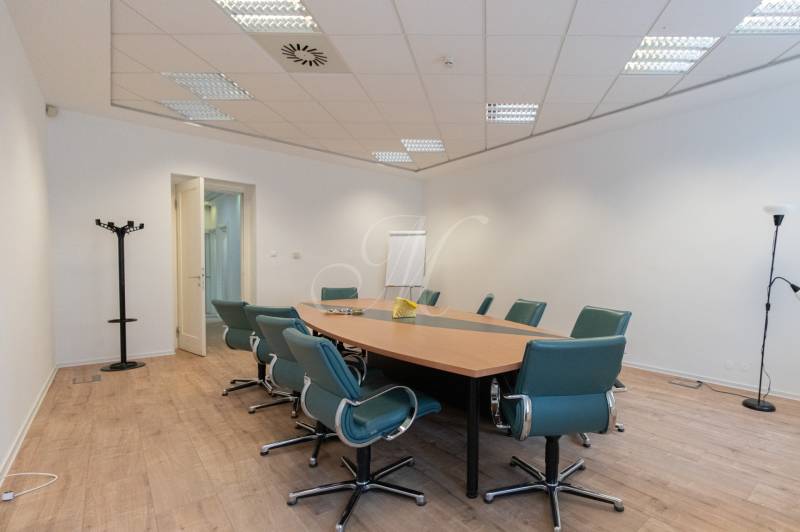 Conference room with wood-patterned flooring, a round table, and green chairs.